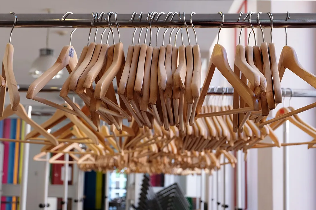 Photograph of metal clothes rails holding wooden hangers in a retail setting; illustrative photo input, not the same product as the drawing